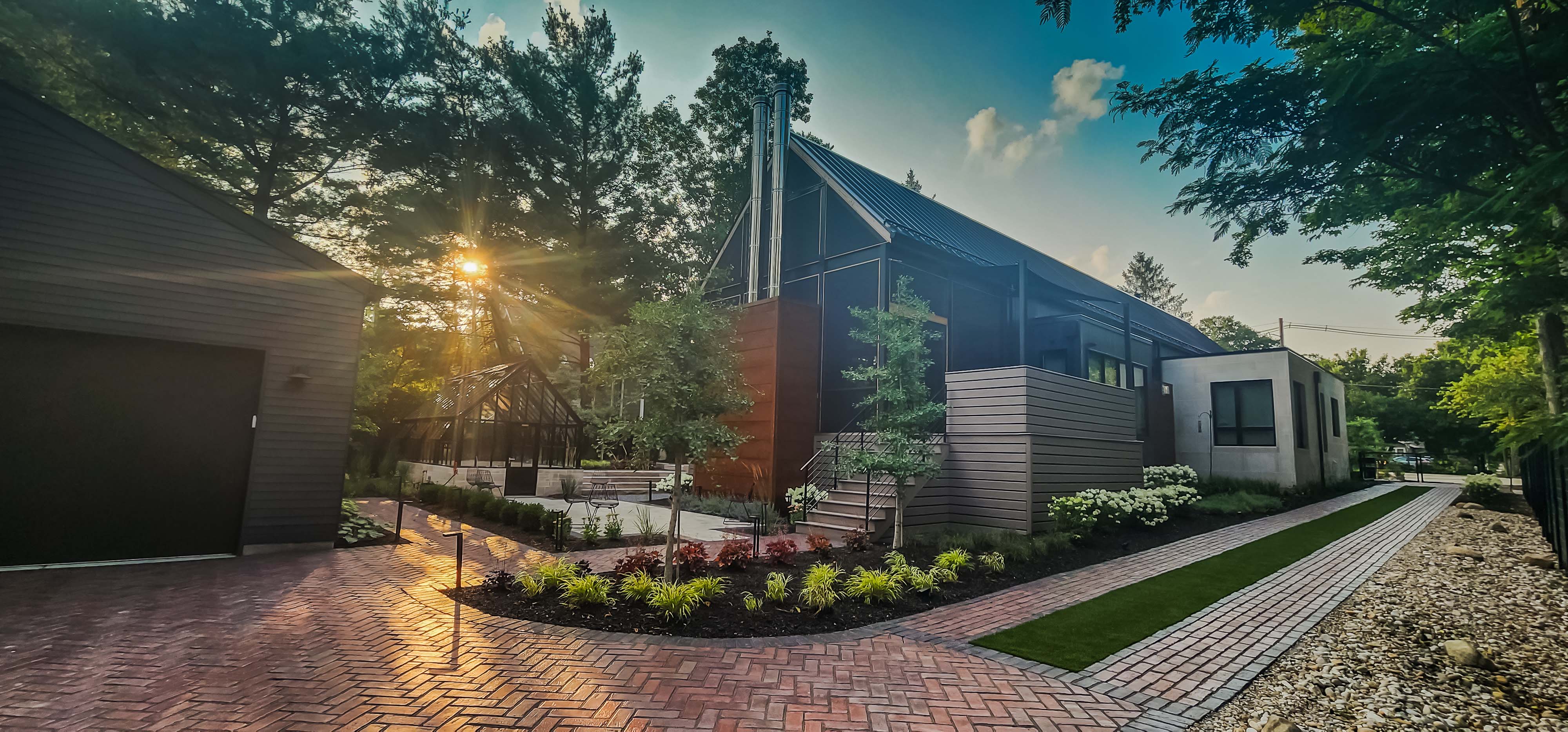 Brick Driveway and landscaping at modern house with greenhouse at  sunset